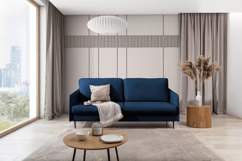 Granatowa sofa w nowoczesnym salonie z beżowymi zasłonami, drewnianym stolikiem i dekoracjami w stylu boho