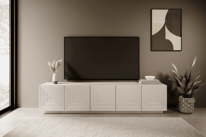 Niska szafka RTV z geometrycznymi frontami w minimalistycznym salonie z telewizorem opartym o ścianę.