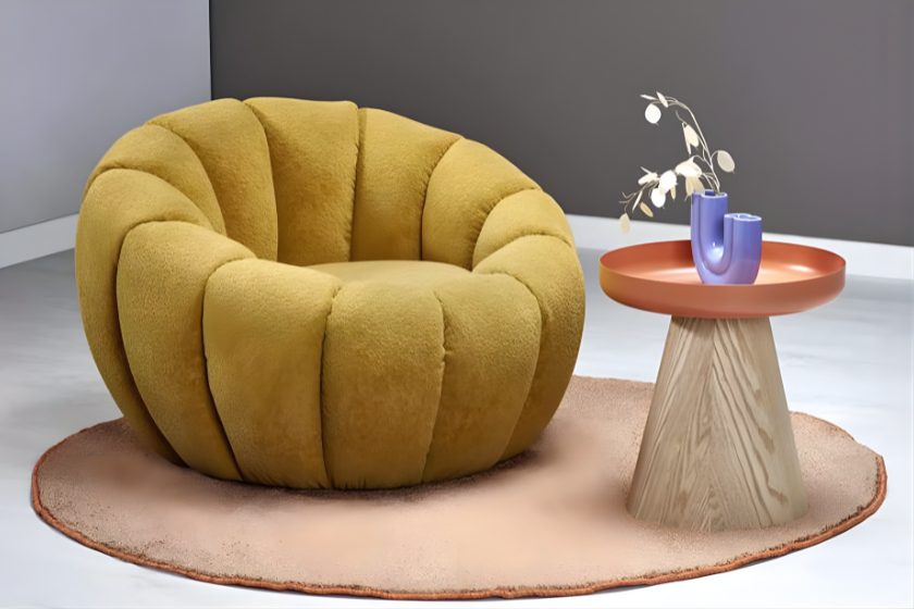 Okrągły żółty fotel o miękkiej, puchatej fakturze obok designerskiego stolika na pastelowym dywanie