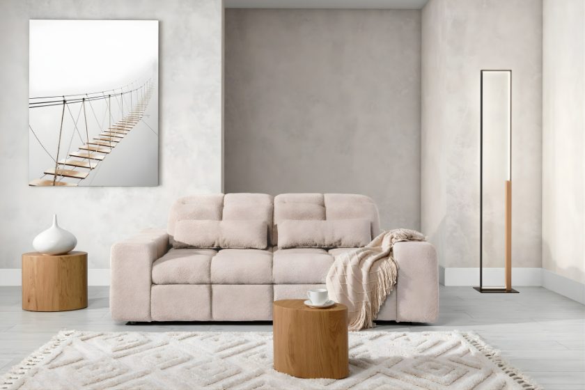 Przytulny salon z beżową sofą o miękkiej strukturze, drewnianymi stolikami i minimalistycznymi dodatkami