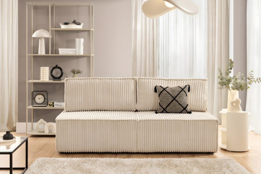 Jasny salon z kremową sofą o ryflowanej strukturze, minimalistycznymi dodatkami i delikatną paletą kolorów